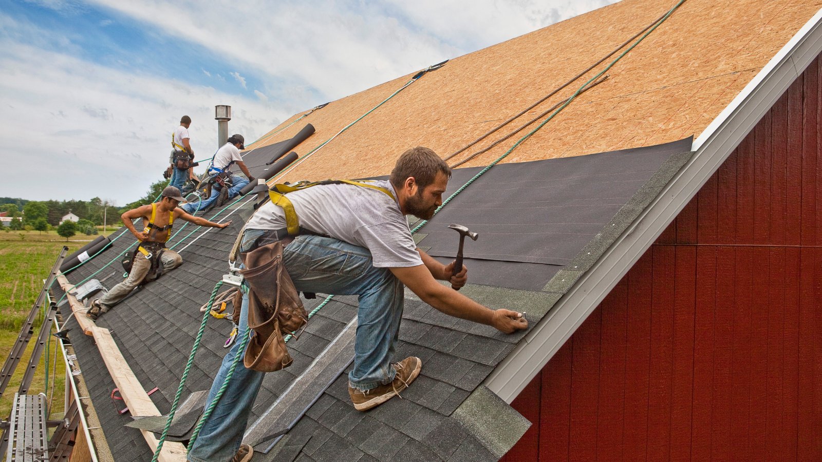 Workman install roof on rural building